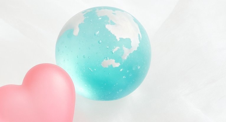 白い布の上に並んだ水色の地球とピンクのハートで、世界に広がるレイキと地球への愛を表現したイメージ写真