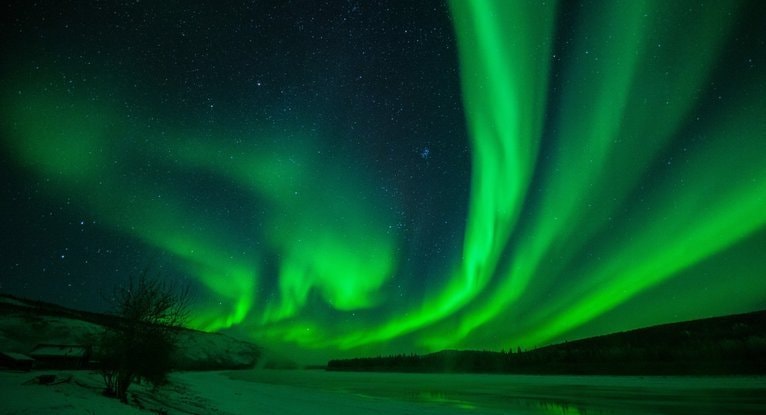 星がまたたく夜空に緑のオーロラが広がる静かな雪原で、宇宙エネルギーとレイキのつながりをイメージした写真