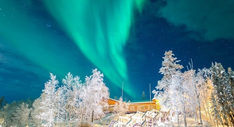 冬の夜空にオーロラが広がる雪のロッジと階段で、臼井霊気と宇宙エネルギーのつながりをイメージした写真