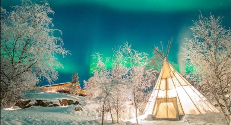雪原に立つティピと白い木々の上空に青緑のオーロラが広がり、レイキヒーリングと大地のぬくもりをイメージした夜景の写真