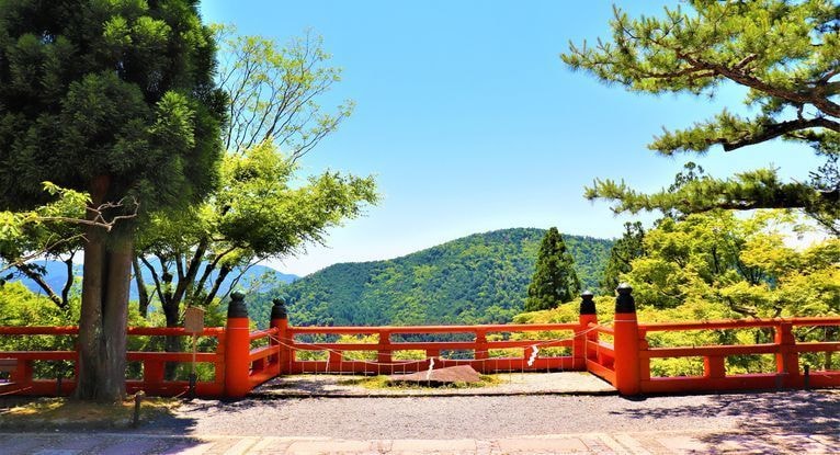 京都・鞍馬山の朱色の欄干越しに、新緑の山並みと青空が広がるレイキゆかりの風景