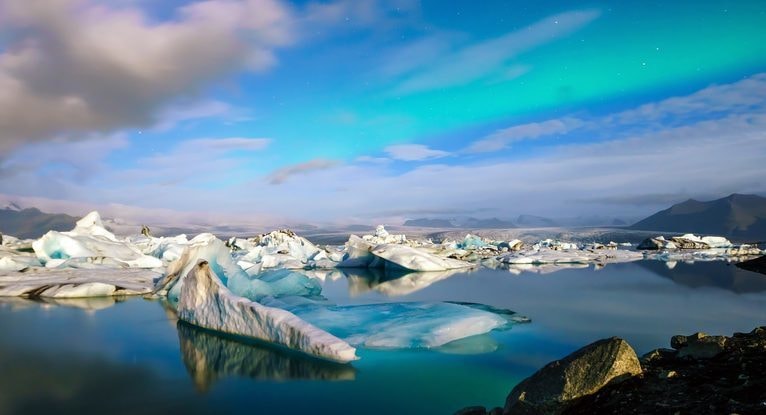 氷河湖の上空に淡い青いオーロラが広がる静かな風景で、レイキと地球のエネルギーのつながりをイメージした写真